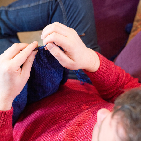 Man knitting wearing red jumper